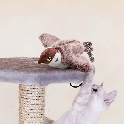 White cat reaching up to bat the brown FlutterChirp plush bird toy on a cat tree platform