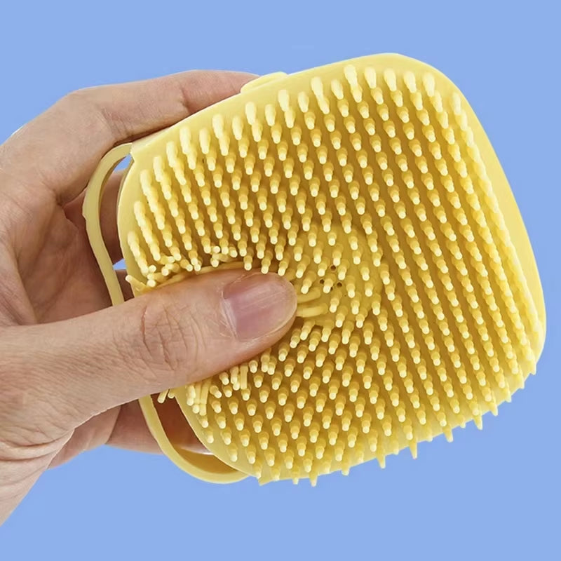 Hand holding the teal silicone bath brush while lathering shampoo onto a dog's fur