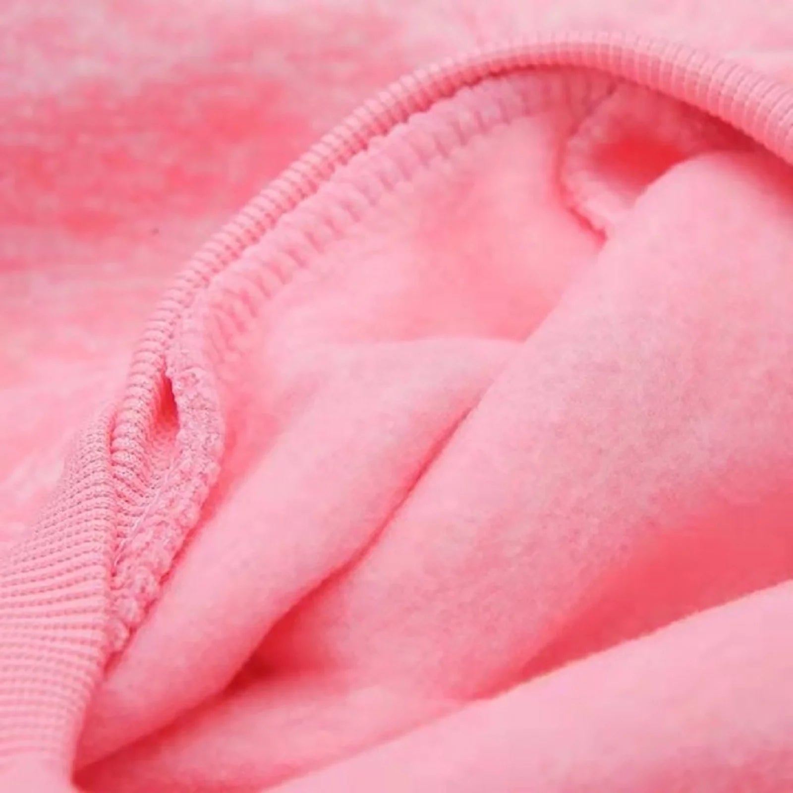 Close-up of pink dog hoodie fabric showing the soft knit texture and stitched seam detail