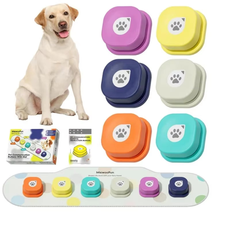 Six colorful talking buttons in purple, yellow, navy, cream, orange, and teal next to a Labrador and packaging box