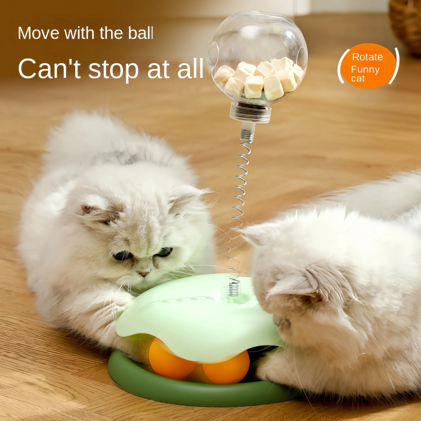 Two cats pawing together at a green puzzle toy's clear treat ball mounted on a spring