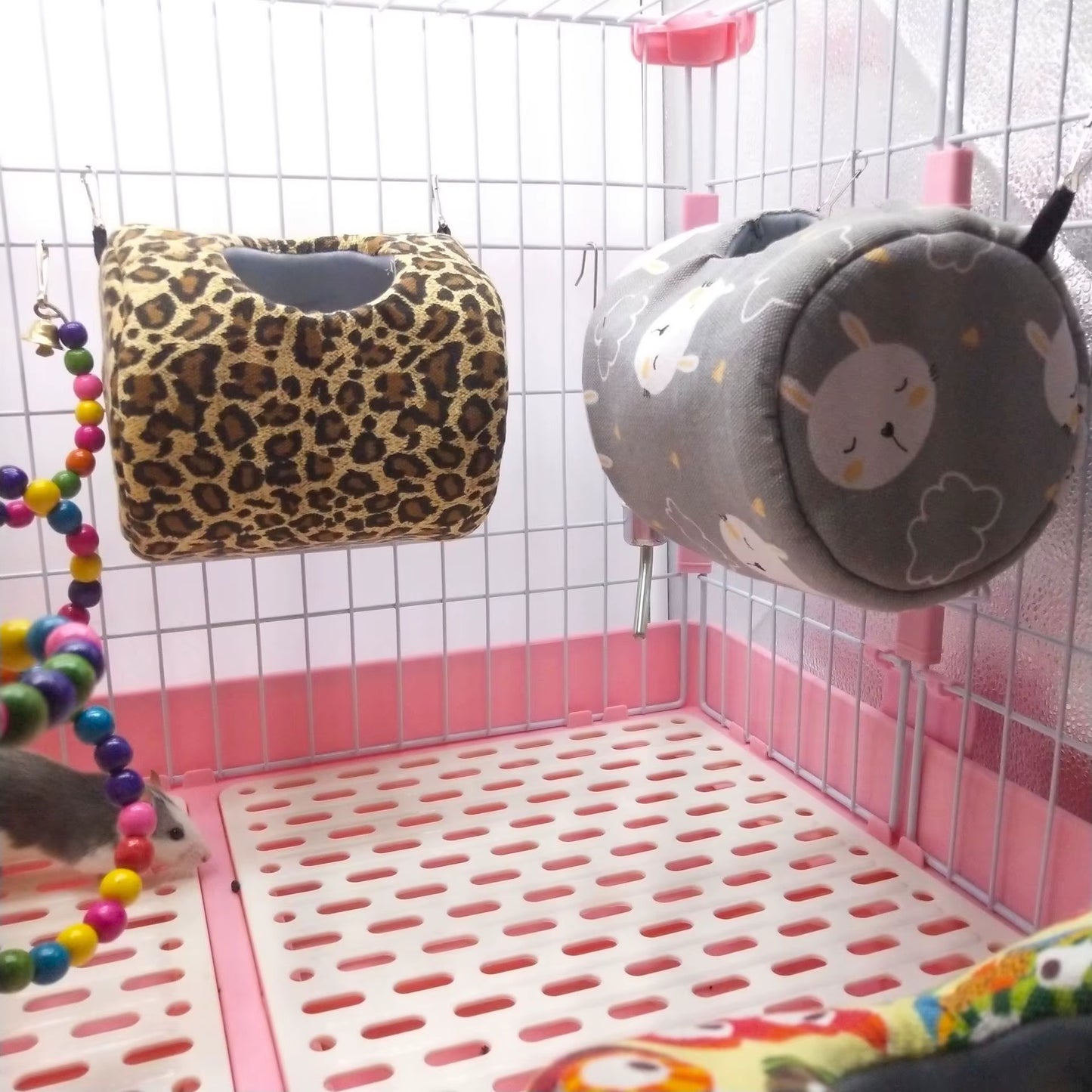 Leopard print and sheep print hammock beds hanging side by side inside a small pet cage