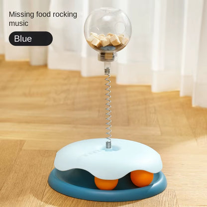 Blue puzzle toy base with a clear treat ball on a spring and two orange balls visible underneath
