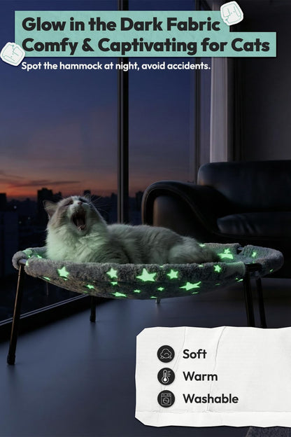 White cat yawning while lying in the elevated cat bed, its star pattern glowing green at night